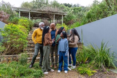 Multigenerational african american family gathering in garden with pergola and stone steps