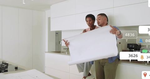 Couple reviewing blueprint at modern kitchen island for renovation planning and design