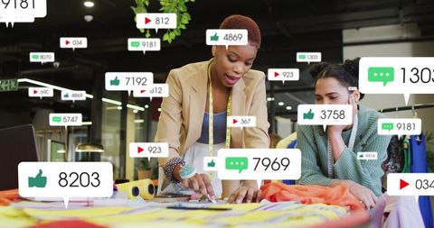 Fashion designers collaborating over colorful fabric swatches with social media engagement overlays
