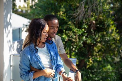 Couple Embracing on Balcony Amid Lush Greenery