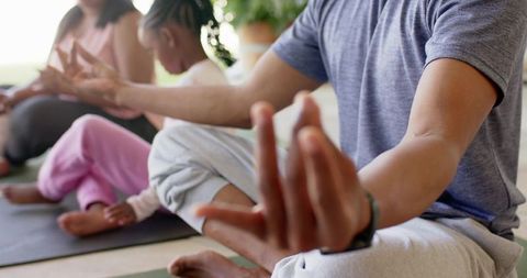 Multiracial family practicing mindful meditation at home on yoga mats