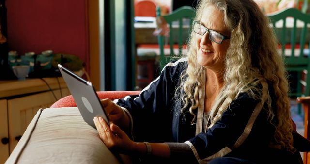 Smiling Senior Woman with Curly Hair Using Digital Tablet at Home - Download Free Stock Images Pikwizard.com