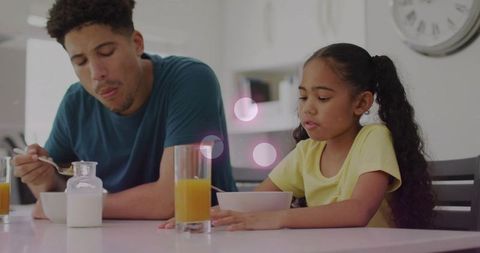 Father and daughter sharing cozy morning breakfast at kitchen table with cereal and juice