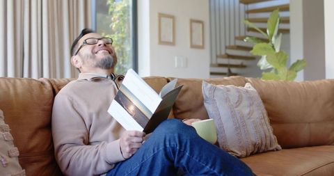 Relaxed Man Enjoying Book and Coffee on Couch with Cozy Home Interior