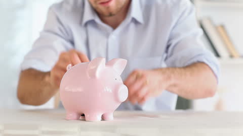 Man Saving Money with Pink Piggy Bank at Home
