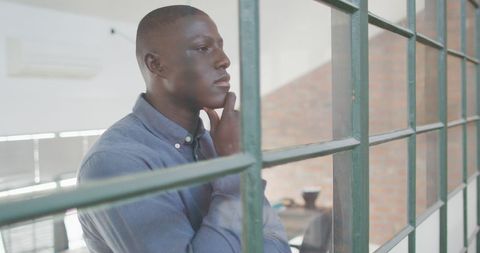 Pensive Businessman Looking through Office Window