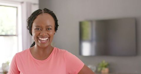 Joyful woman smiling in modern living room wearing pink active top lifestyle portrait