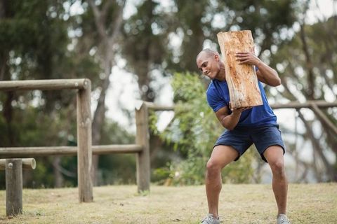 Man Lifting Log for Outdoor Strength Training in Park