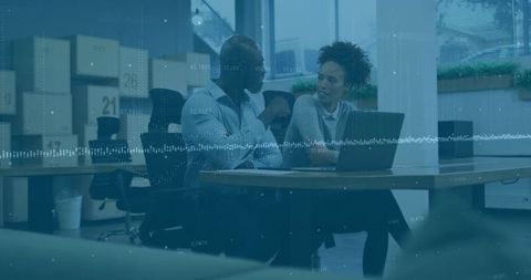 Coworkers collaborating over laptop in open office with waveform data visualization overlay