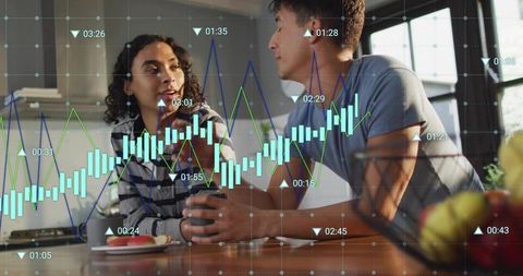 Young couple discussing investments with candlestick chart overlay on kitchen counter