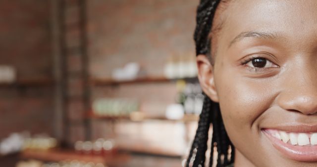 This image captures a close-up of a smiling woman with braided hair in a well-lit indoor setting. The background is subtly blurred, keeping the focus on her happy expression. Ideal for content related to positivity, youthfulness, personal stories, mental health, lifestyle blogs, or advertisements targeting a diverse audience.