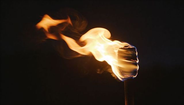 Burning matchstick close-up emitting dynamic flame, blue ember and smoke on dark background