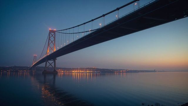 Majestic Suspension Bridge Illuminated at Dusk Over Tranquil Bay
