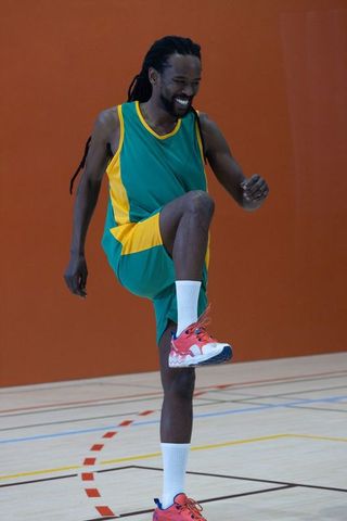 Athlete energized with knee lift on indoor basketball court
