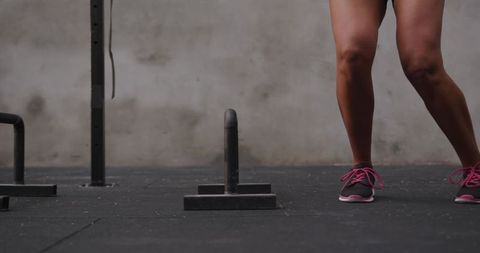 Woman Performing Squat in Gym near Fitness Equipment