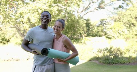 Laughing Couple with Yoga Mats Enjoying Outdoors in Park