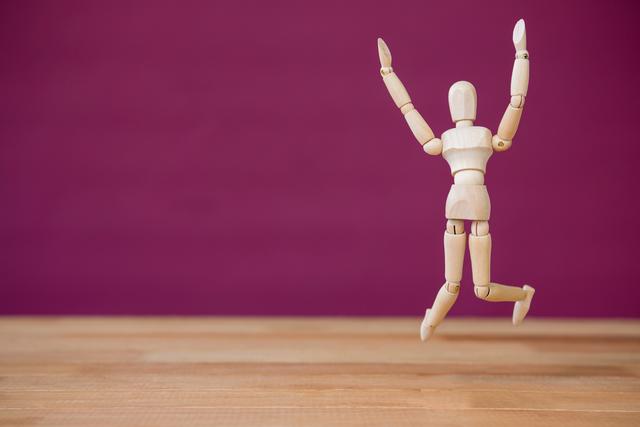 Conceptual image of figurine jumping on a wooden floor