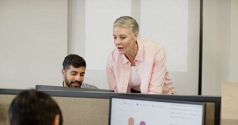 Coworkers collaborating over cubicle partition in modern office