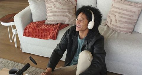 Mid-adult man recording podcast at home wearing headphones and talking into microphone