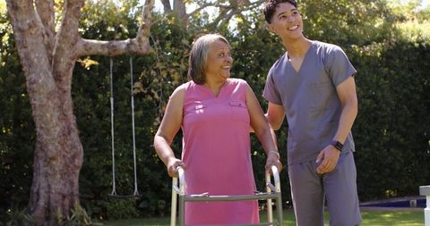 Physiotherapist assisting senior woman with walker outdoors