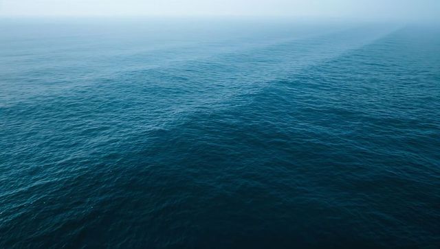 Tranquil Blue Ocean with Gentle Waves under Hazy Sky