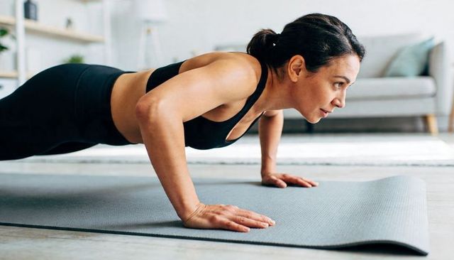 Woman doing push-up on home mat demonstrating core strength focused fitness routine