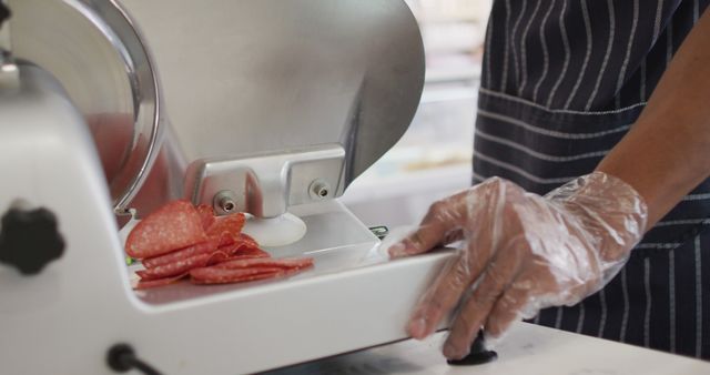 Image of hands of biracial waiter using meat cutting machine. coffee and bistro shop, running small independent business.