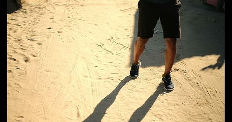 Low section of runner on beach sand in sunlight