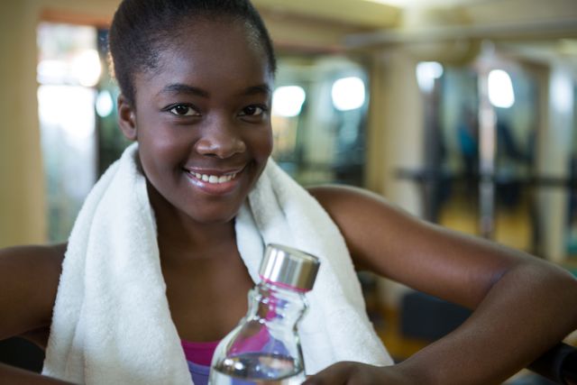 Portrait of happy woman holding water bottle after workout in gym