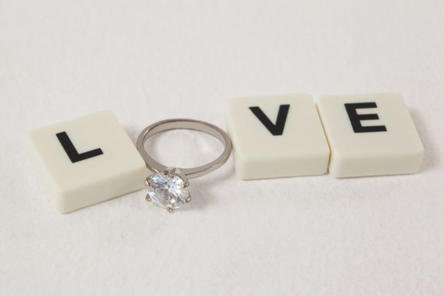 Diamond ring between white blocks displaying love message on white background