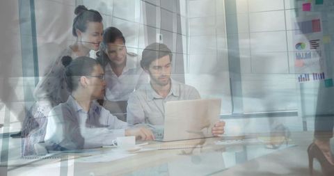 Team collaborating over laptop in modern office, reviewing charts and planning strategy