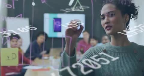 Woman presenting on glass board writing data and diagrams while team collaborates in meeting