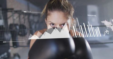 Female boxer focusing through boxing gloves with digital hud overlay for training