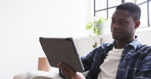 Relaxed Young Man Using Tablet at Home in Modern Setting