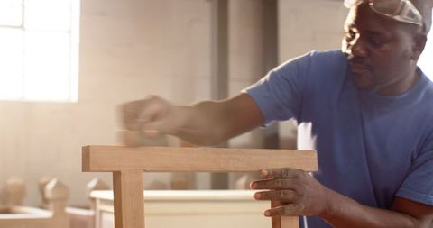 Skilled craftsman sanding wood in sunlit workshop