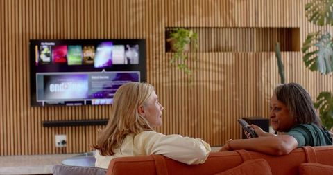 Diverse women relaxing in modern living room with television