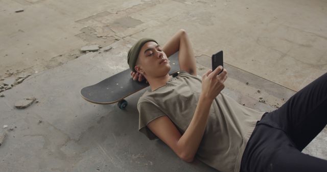 Teenage Boy Relaxing with Smartphone on Skateboard in Abandoned Building - Download Free Stock Images Pikwizard.com