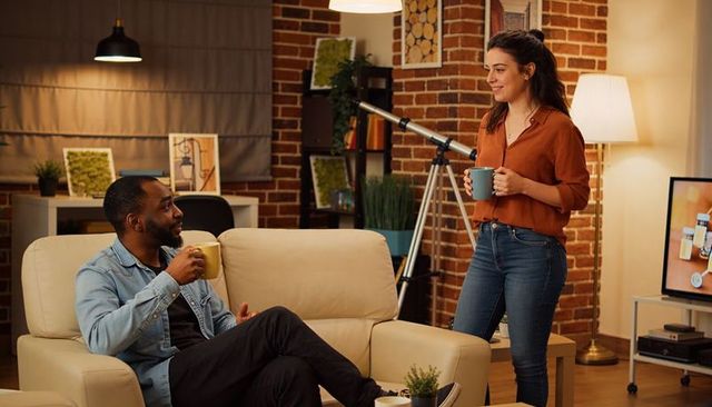 Couple sharing cozy evening coffee in brick living room with telescope and warm lighting