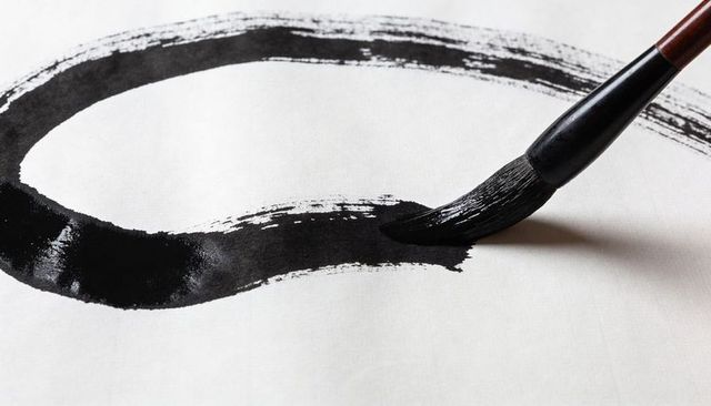 Zen ink brush stroke creating bold enso circle on white paper, calligraphy brush texture