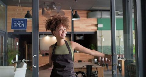 Welcoming customers at modern cafe entrance opening glass doors under open sign
