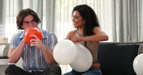 Happy couple preparing balloons for birthday celebration at home