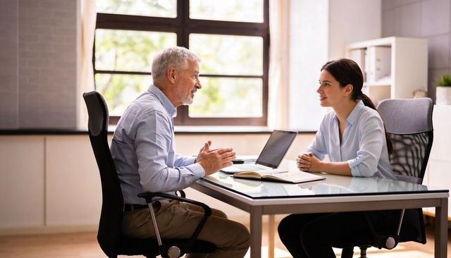 Senior executive discussing strategy with young professional in bright office meeting