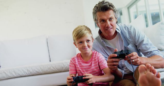 Father and son playing video games together on sofa - Download Free Stock Images Pikwizard.com