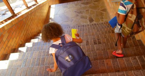 Young Students Walking Down School Staircase with Backpacks