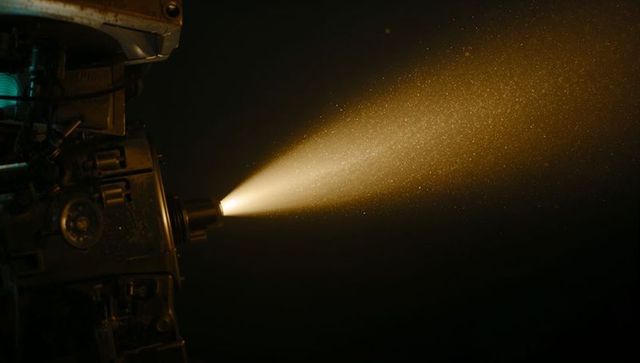 Vintage Film Projector Casting Beam of Light in Dark Cinema