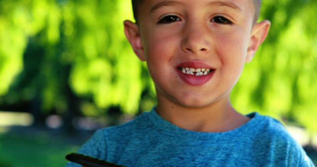 A young boy smiling proudly outdoors, showcasing his freshly lost tooth. Ideal for themes of childhood, growth, and happiness. Suitable for educational materials, pediatric dentistry services, parenting blogs, and family-centric advertisements.