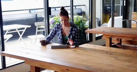Businesswoman Relaxing with Tablet and Coffee in Modern Office Cafe