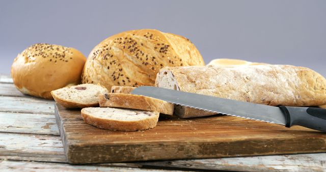 Various bread loaves with knife on wooden table