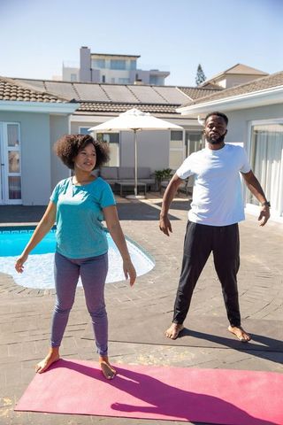 Couple Doing Outdoor Yoga by Pool on a Sunny Day