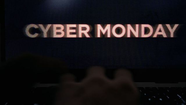 Blurred hands typing on backlit laptop keyboard showing cyber monday text for ecommerce